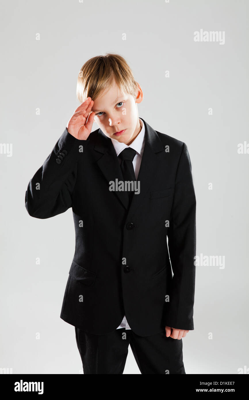 Ritratto in studio di grave alla ricerca giovane ragazzo in abito nero salutando Foto Stock
