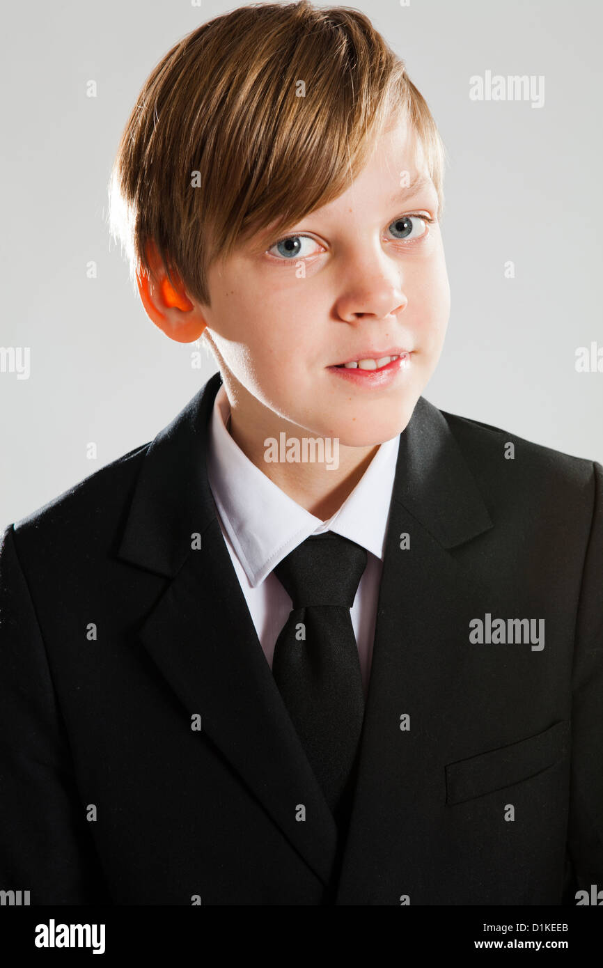 Ritratto in studio di un sorridenti giovane ragazzo indossa abito nero Foto Stock