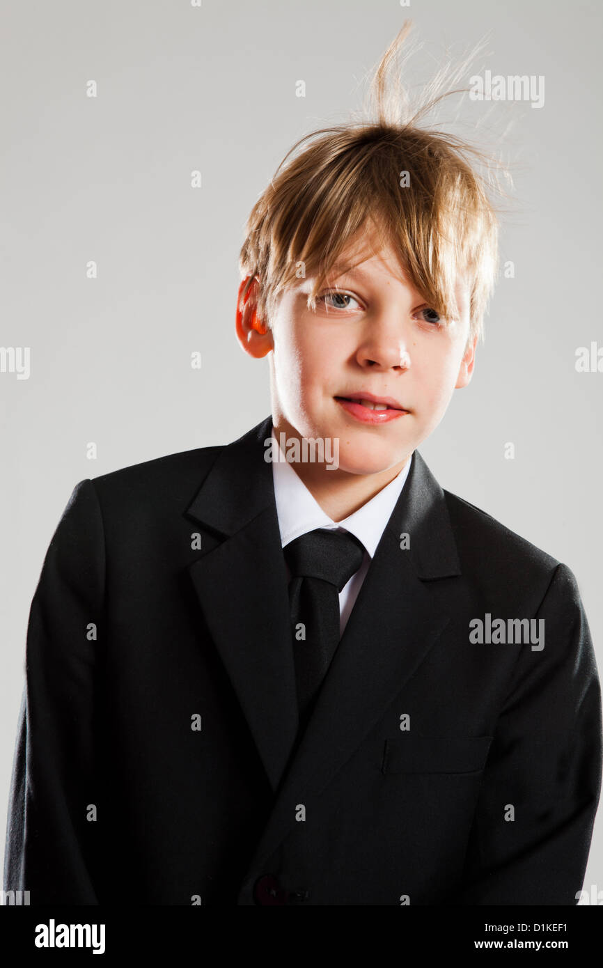 Ritratto in studio di sorridente e rilassato giovane ragazzo in abito nero con il vento che soffia capelli Foto Stock