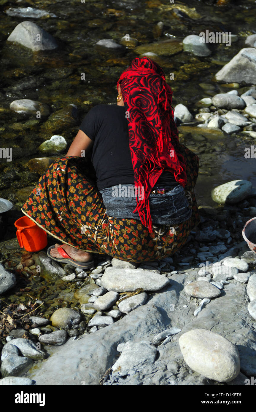 Una donna lava le stoviglie in un flusso in Nepal rurale vicino Phokara, Nepal Foto Stock