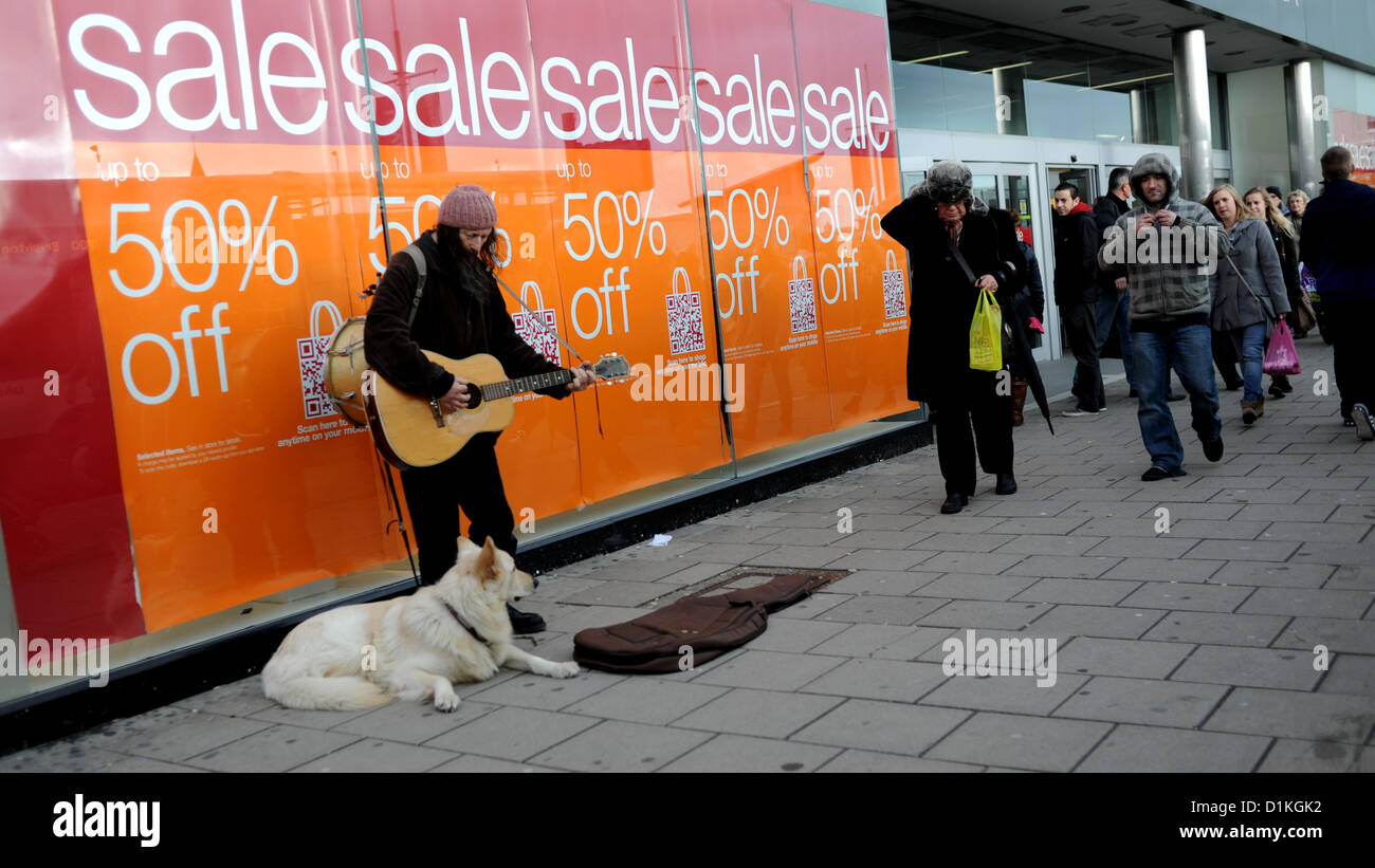 Brighton Sussex Regno Unito 27 dicembre 2012 - Un giocatore di strada gioca oggi contro una vetrina del negozio M&S Marks e Spencer piena di poster di vendita mentre gli acquirenti continuano con la frenetica caccia agli affari fotografia scattata da Simon Dack/Alamy Live News Foto Stock