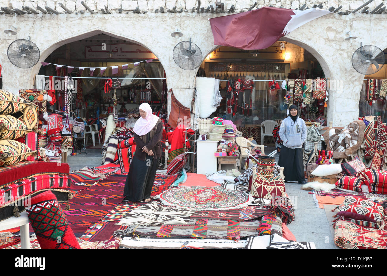 Orazione tessili arabo in vendita in un negozio di Souq Waqif, Doha, Qatar, con negozio di assistenti in attesa di servire i clienti. Foto Stock