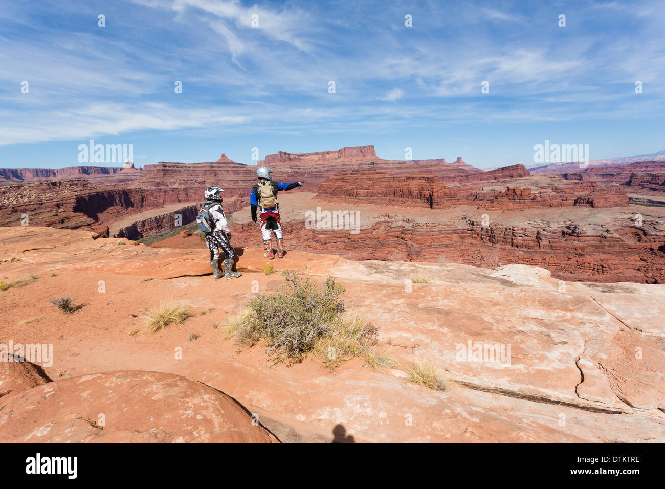 Due off road bikers indossare i caschi in piedi al bordo del canyon presso il Parco Nazionale di Canyonlands, Utah Foto Stock