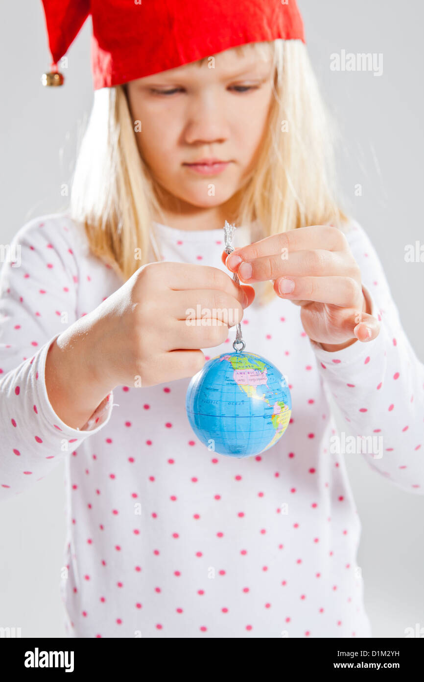 Studio Ritratto di giovane ragazza con red Christmas elf hat holding Globo mondo in mani Foto Stock