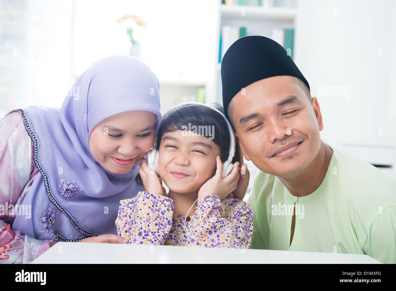 Sud-est asiatico famiglia ascoltare mp3, condividendo le cuffie. Famiglia musulmana stile di vita vivente Foto Stock