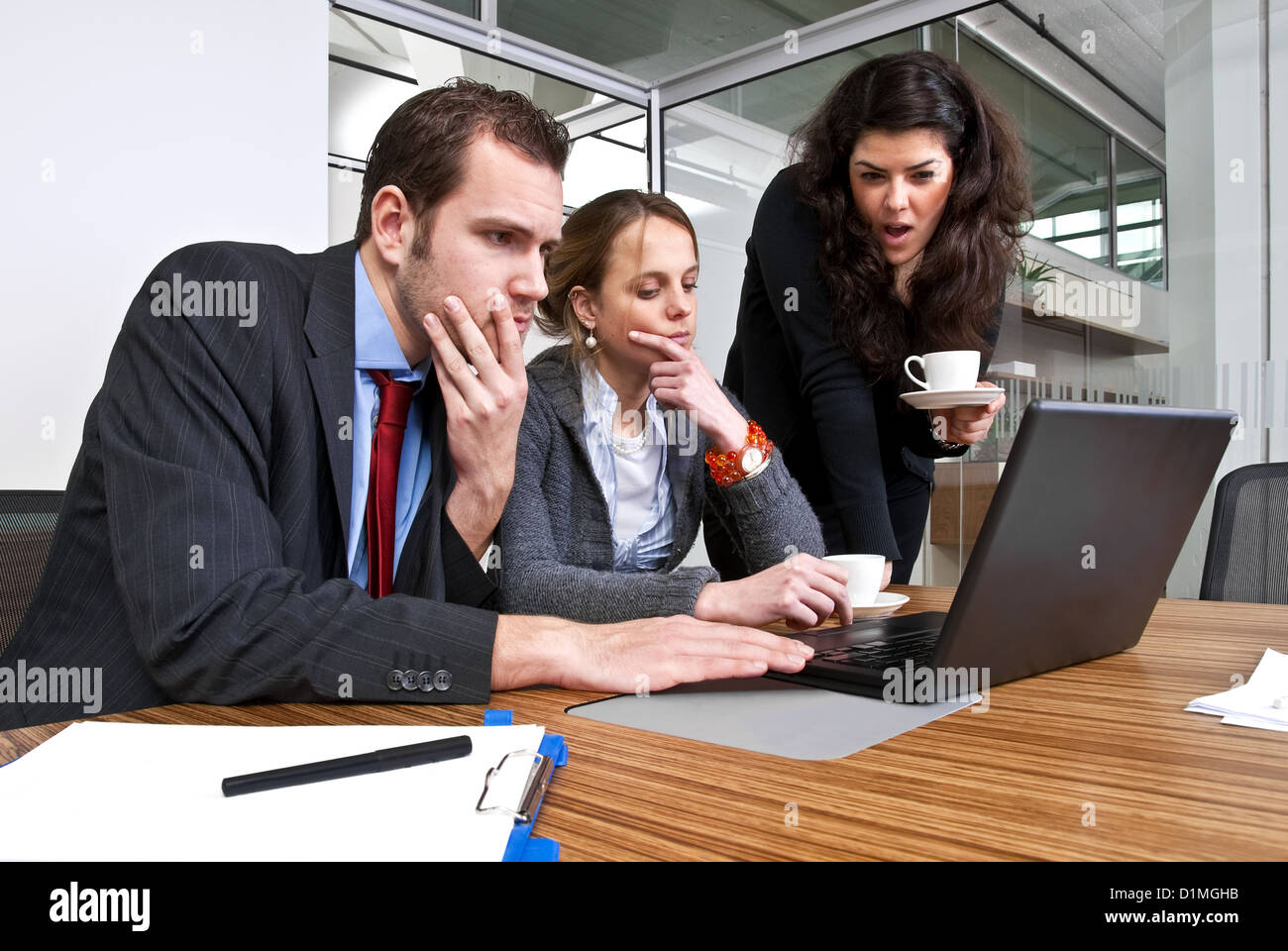 Tre membri dello staff per discutere le questioni finanziarie durante la navigazione di un computer portatile Foto Stock