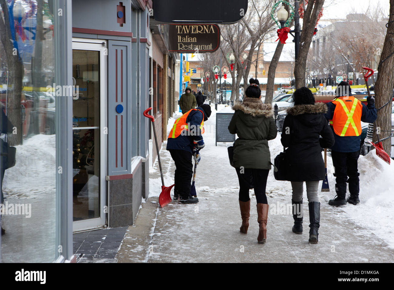 I lavoratori pubblici la rimozione di neve e ghiaccio fuori i marciapiedi in downtown Saskatoon Saskatchewan Canada Foto Stock