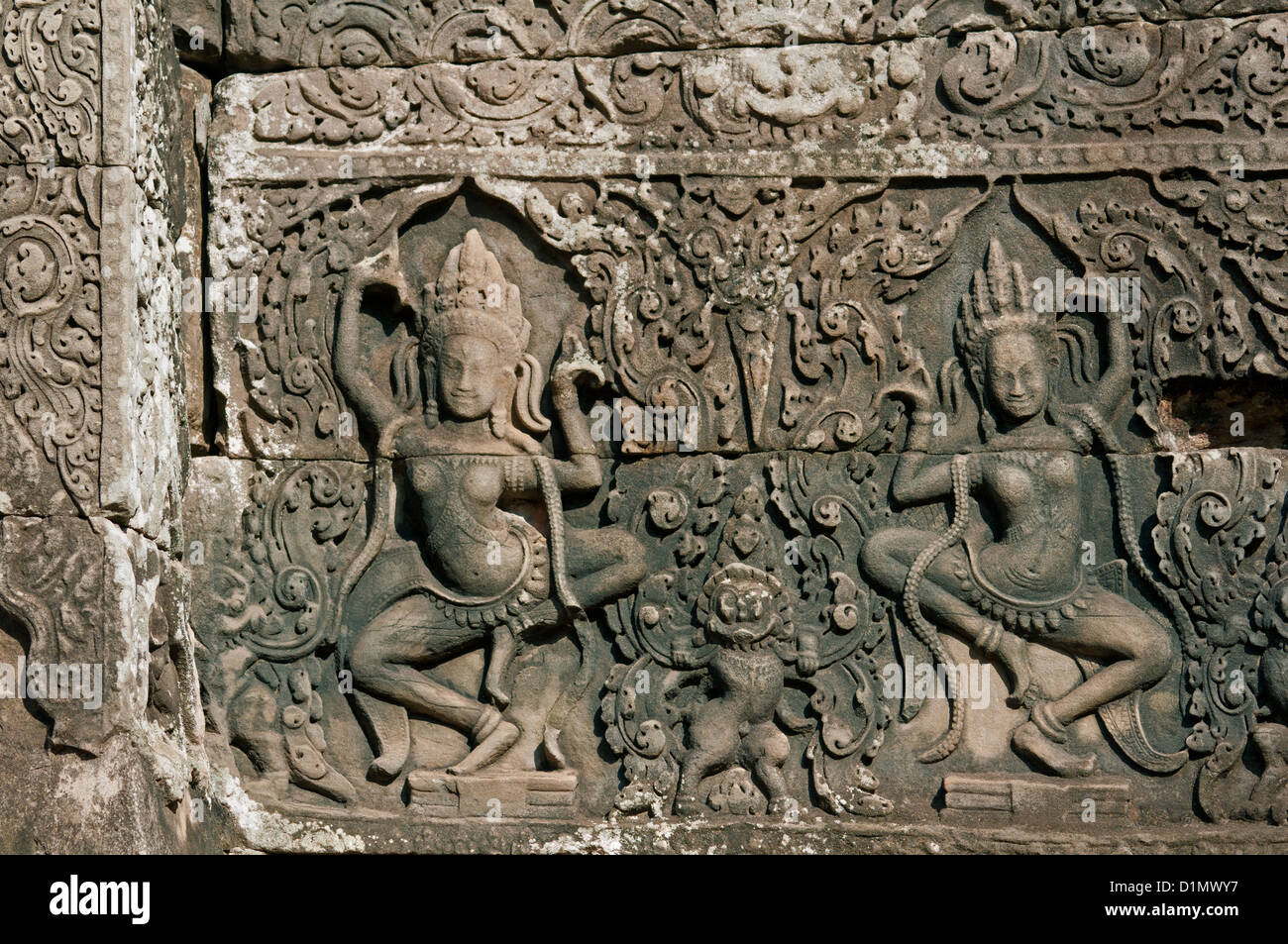 Due danza Apsara incorniciato dalle intricate e foglie intrecciate, modelli di Angkor Thom, Siem Reap, Cambogia Foto Stock