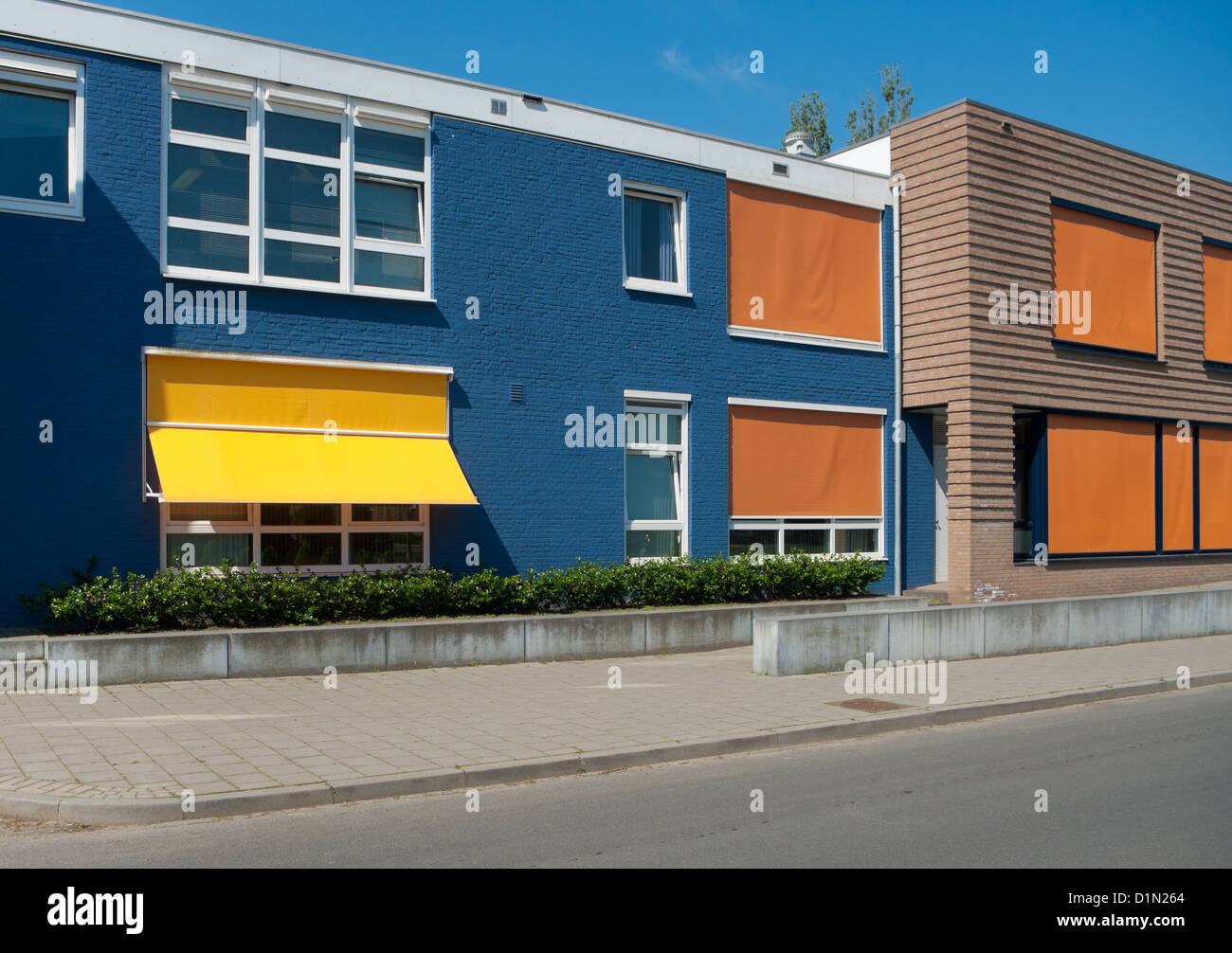 Edificio moderno di colore giallo e con orange ombrelloni in un giorno caldo Foto Stock