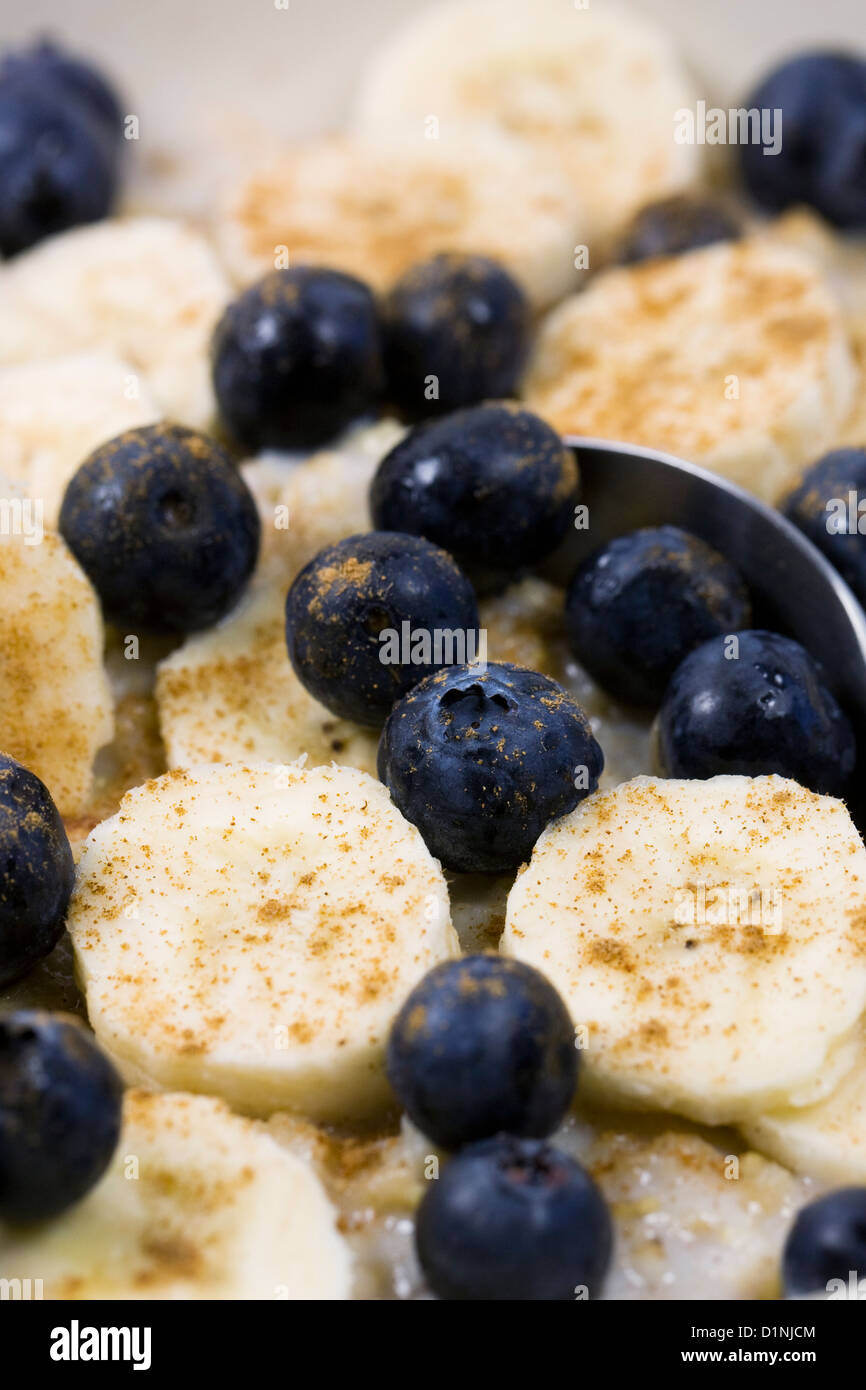 Una sana prima colazione. Porridge con banana, mirtilli e una spolverata di cannella. Foto Stock
