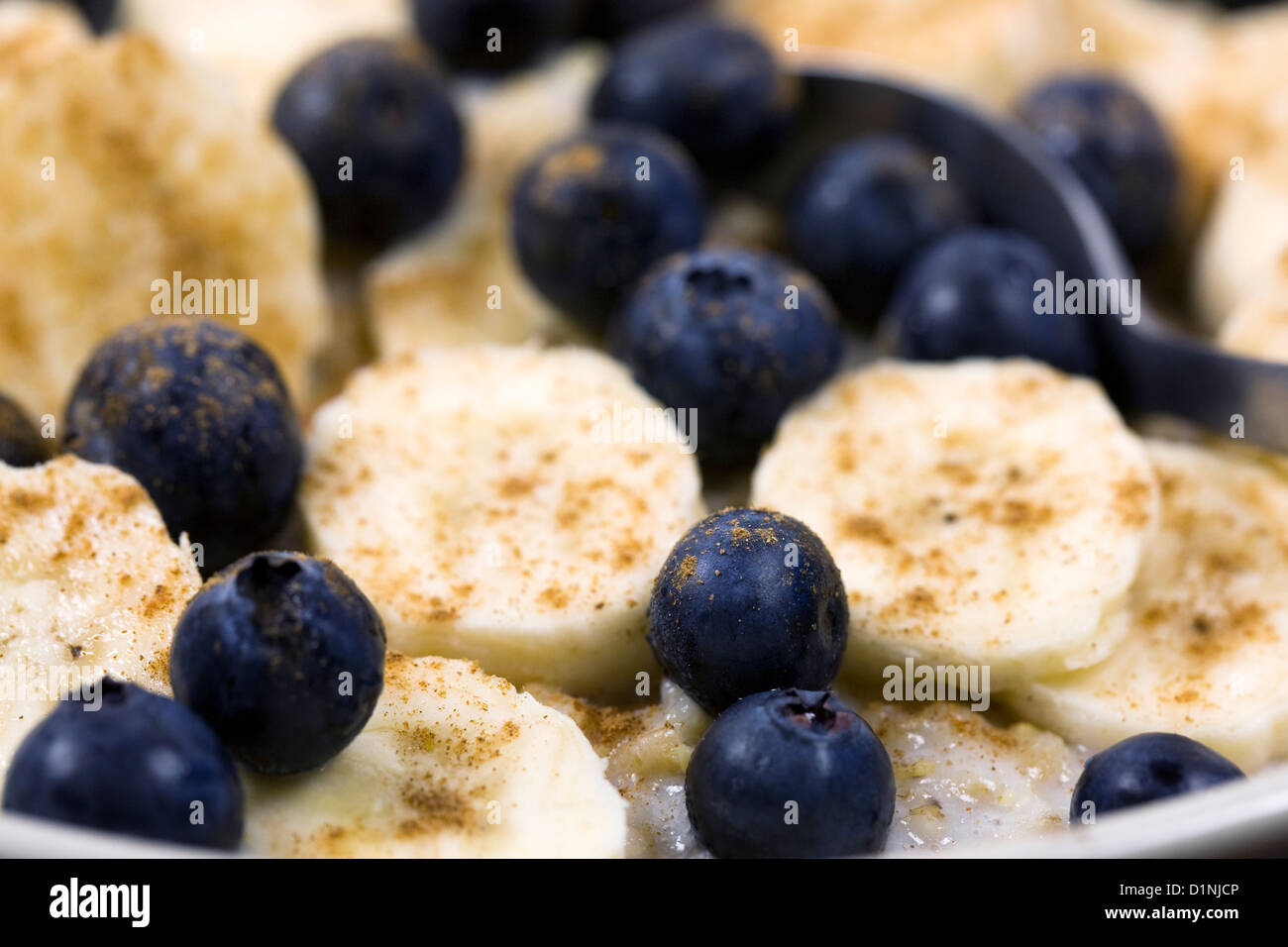 Una sana prima colazione. Porridge con banana, mirtilli e una spolverata di cannella. Foto Stock