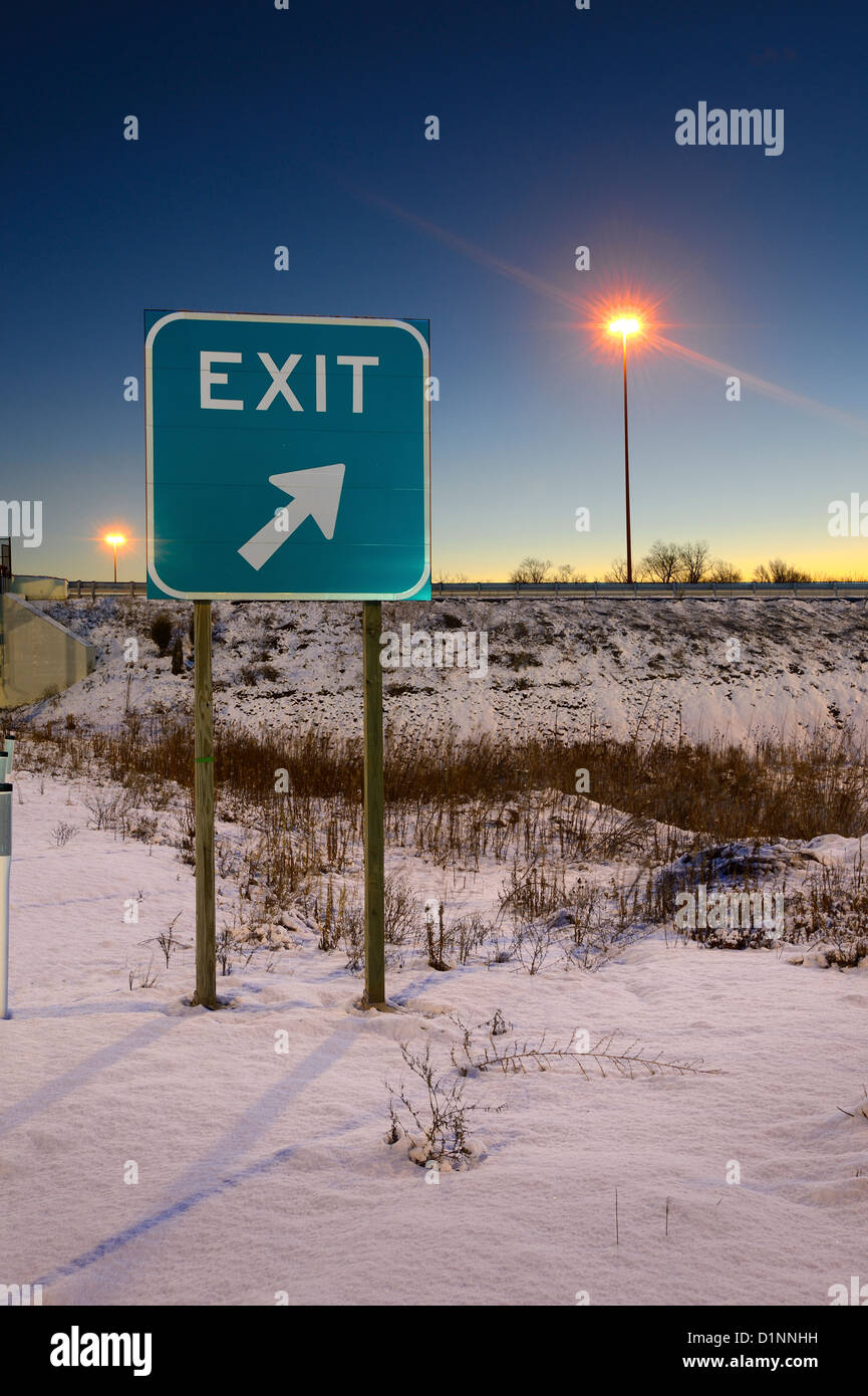 Autostrada uscita segno in inverno all'alba con luce Post Foto Stock