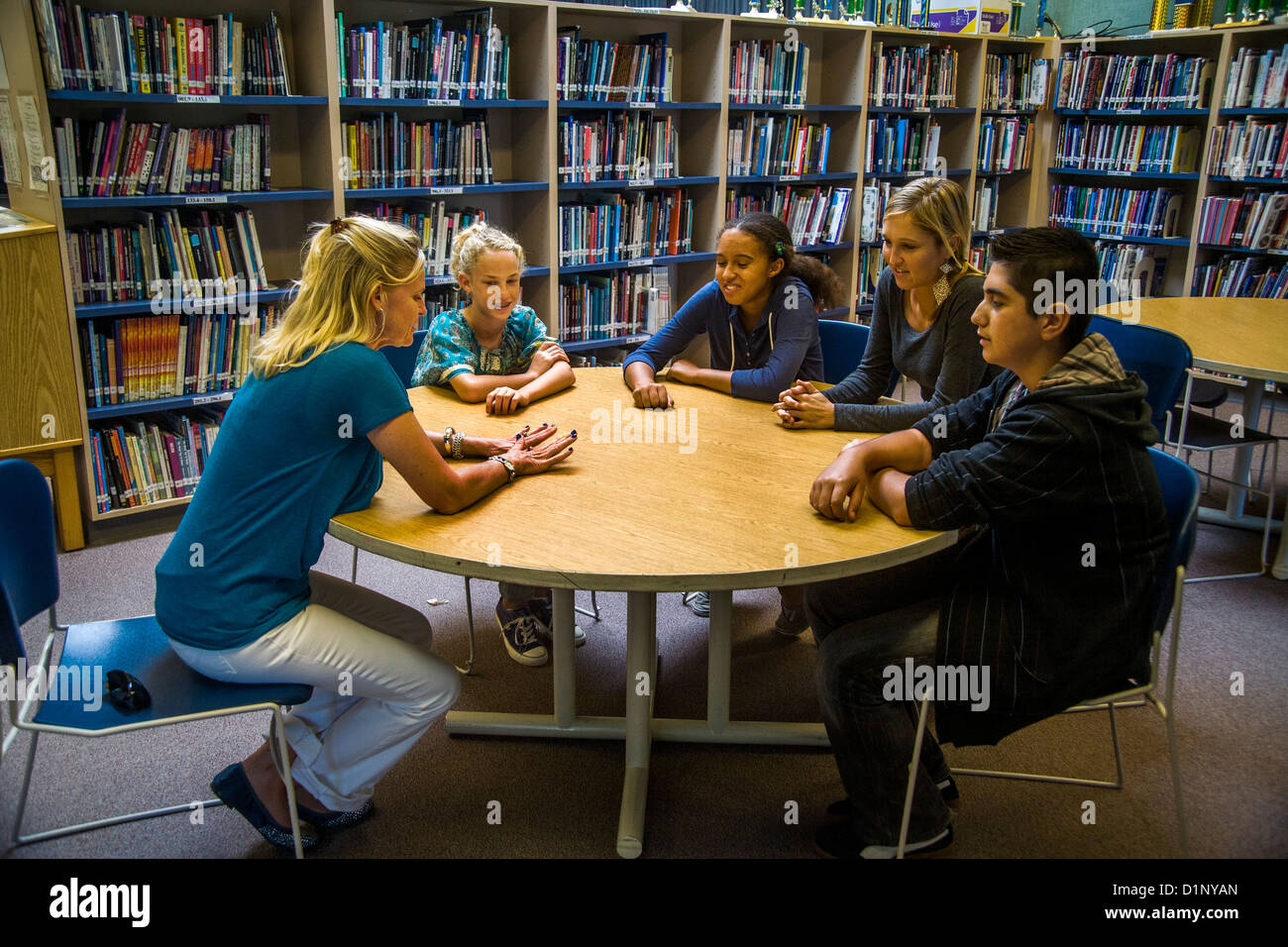 Un junior high school consigliere risponde con un gruppo multietnico di studenti in una San Clemente, CA, biblioteca scolastica. Foto Stock