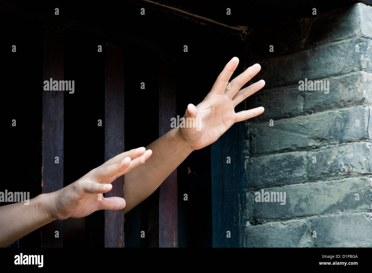 Due mani tratto fuori da cellule in cerca di libertà Foto Stock