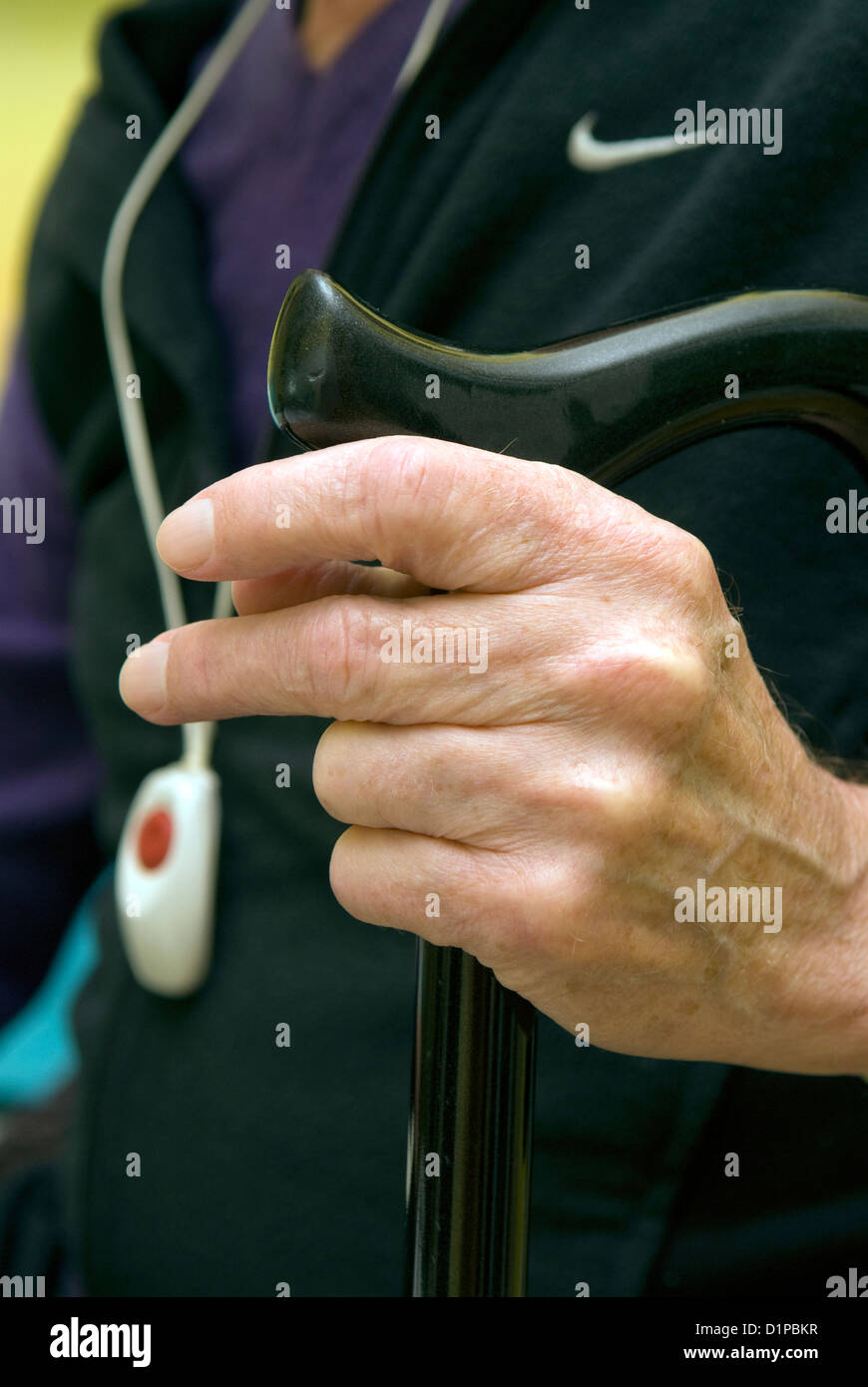 Uomo con disabilità fisica holding bastone & indossando un ciondolo trigger di emergenza Foto Stock