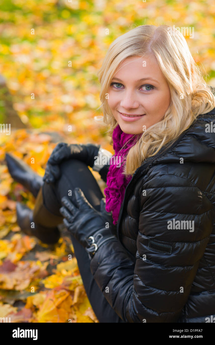 Bella ragazza seduta su una roccia, Colore di autunno lascia sullo sfondo Foto Stock