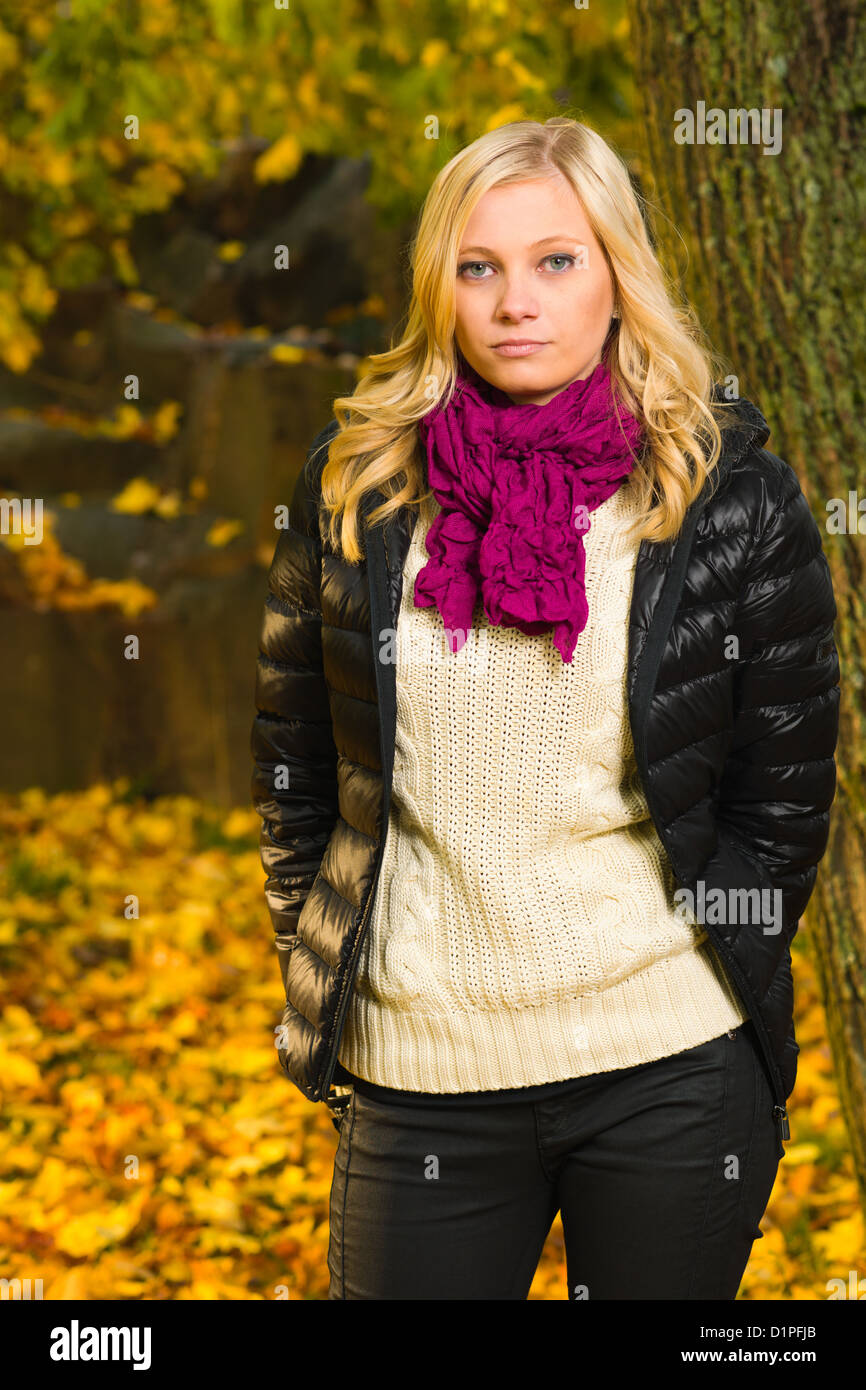Bella ragazza pone su un parco, Colore di autunno lascia sullo sfondo, formato verticale Foto Stock