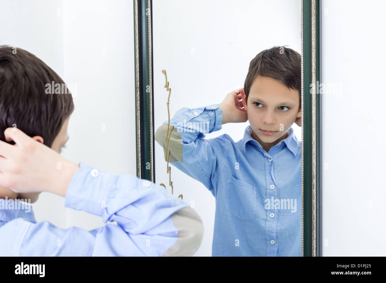 Fotografia orizzontale di un giovane ragazzo pettinare i capelli mentre guardando a se stesso in uno specchio Foto Stock