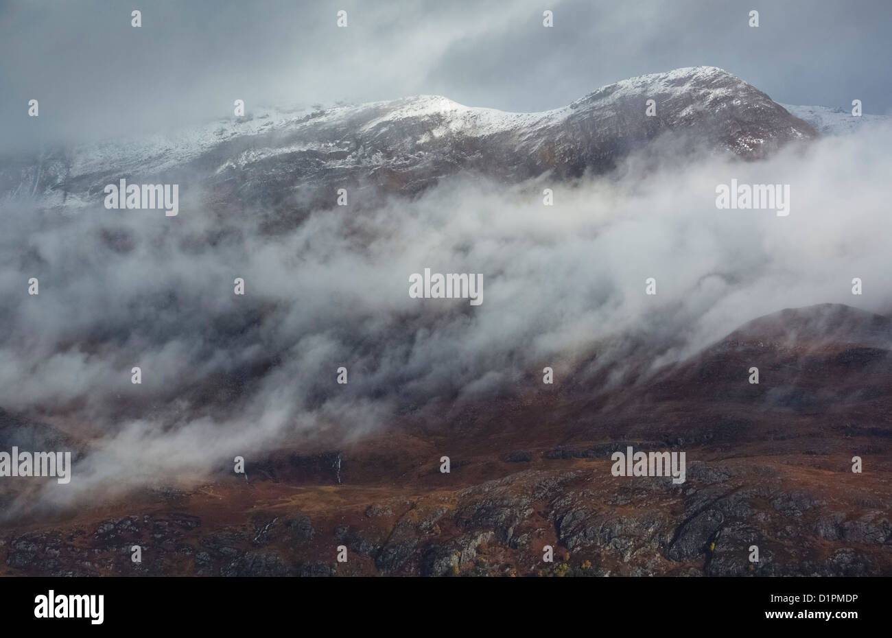 Basse nubi intorno ai vertici della Sgurr Dubh, Sgurr un Tuill Bhain e la caduta di acqua in corrispondenza della sua base vicino al Loch Maree. Foto Stock