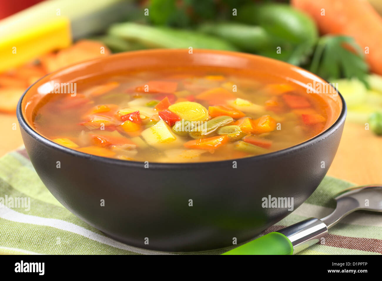 Verdura fresca zuppa di verde fagiolo, pisello, carota, patata, il peperone rosso, il pomodoro e il porro in vaso nero Foto Stock