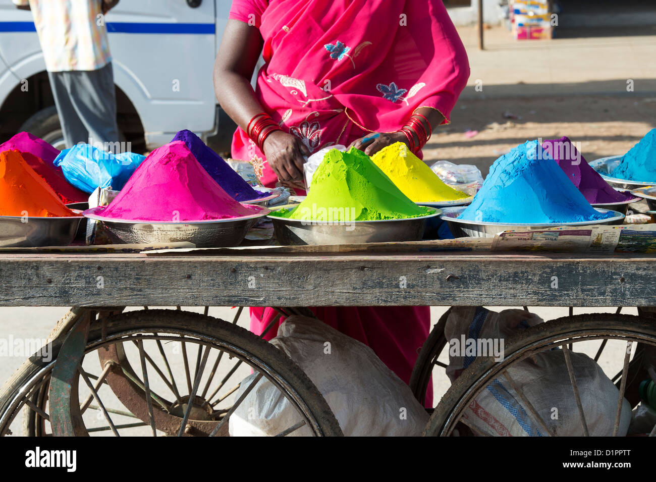 Sud donna indiana vendita di polvere colorata utilizzata per la realizzazione di disegni e modelli rangoli a festival da un carrello sulla strada. India Foto Stock