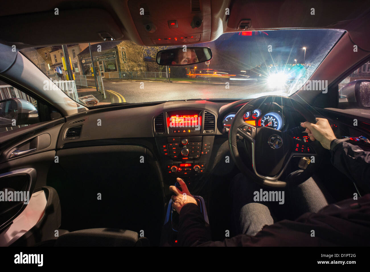 Un autista in attesa per le spie verde per attivare la notte dall'interno dell'auto. Foto Stock