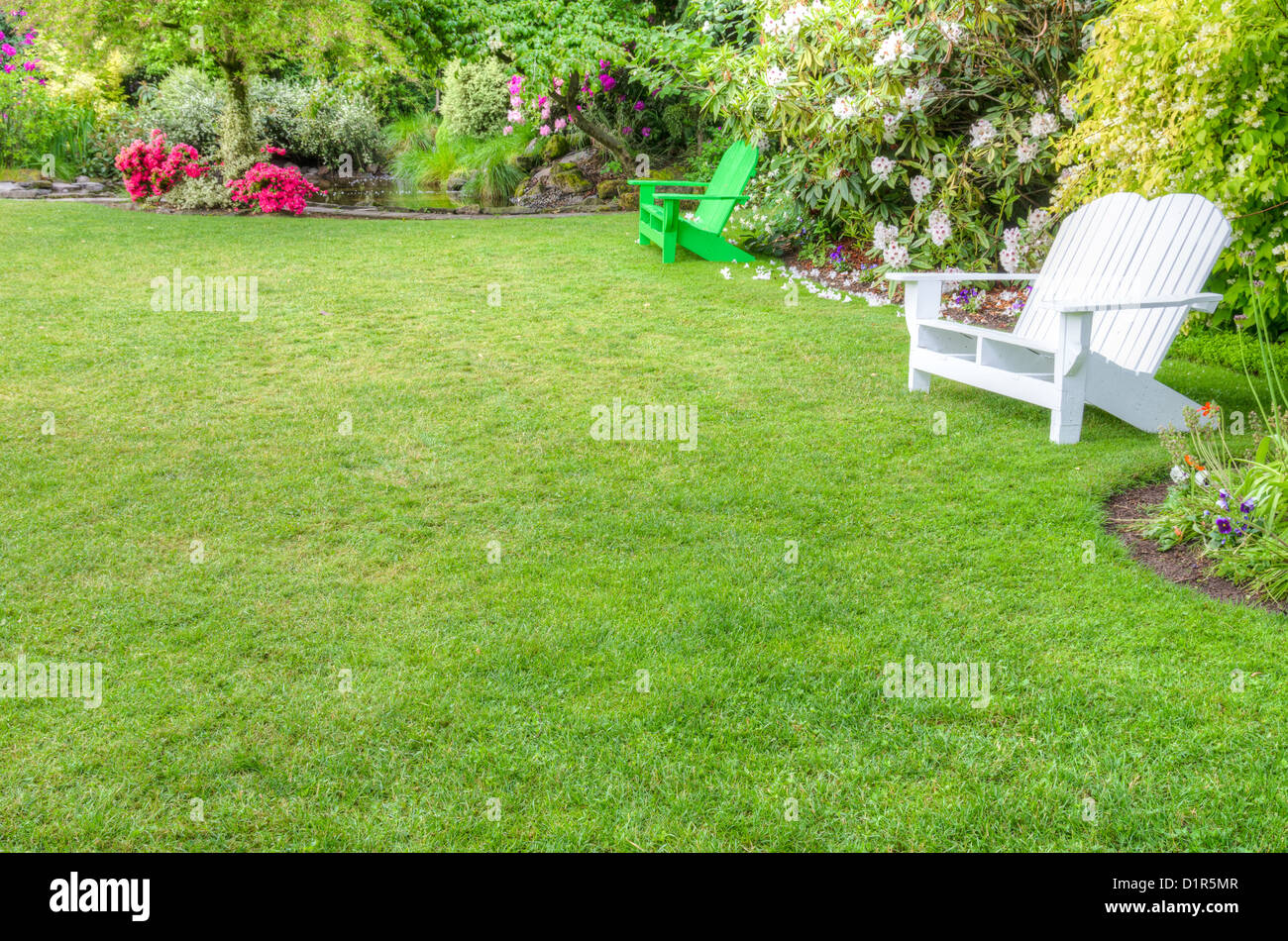 Una scena del giardino con prato verde e panche Foto Stock