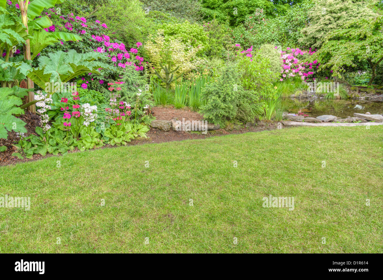 Un giardino scena con rosa azalee e una piscina a specchio Foto Stock