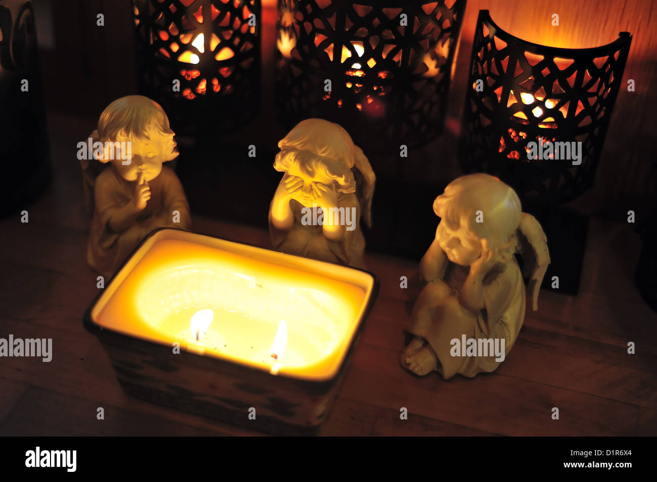 Tre Angeli seduti intorno a una candela Foto Stock