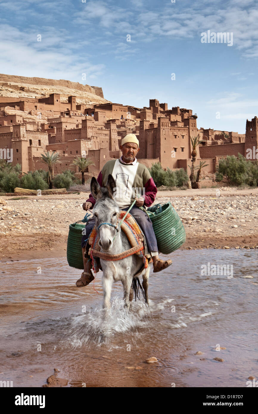 Il Marocco, Ait Ben Haddou, antica fortezza o kasbah o ksar. L'uomo su donkey Attraversamento fiume Tirza. Foto Stock