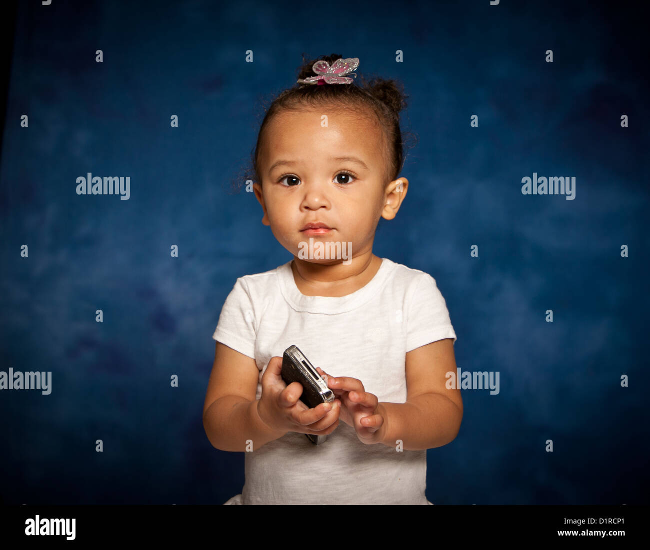 Ritratto in studio di carino razza mista toddler ragazza con un telefono cellulare Foto Stock