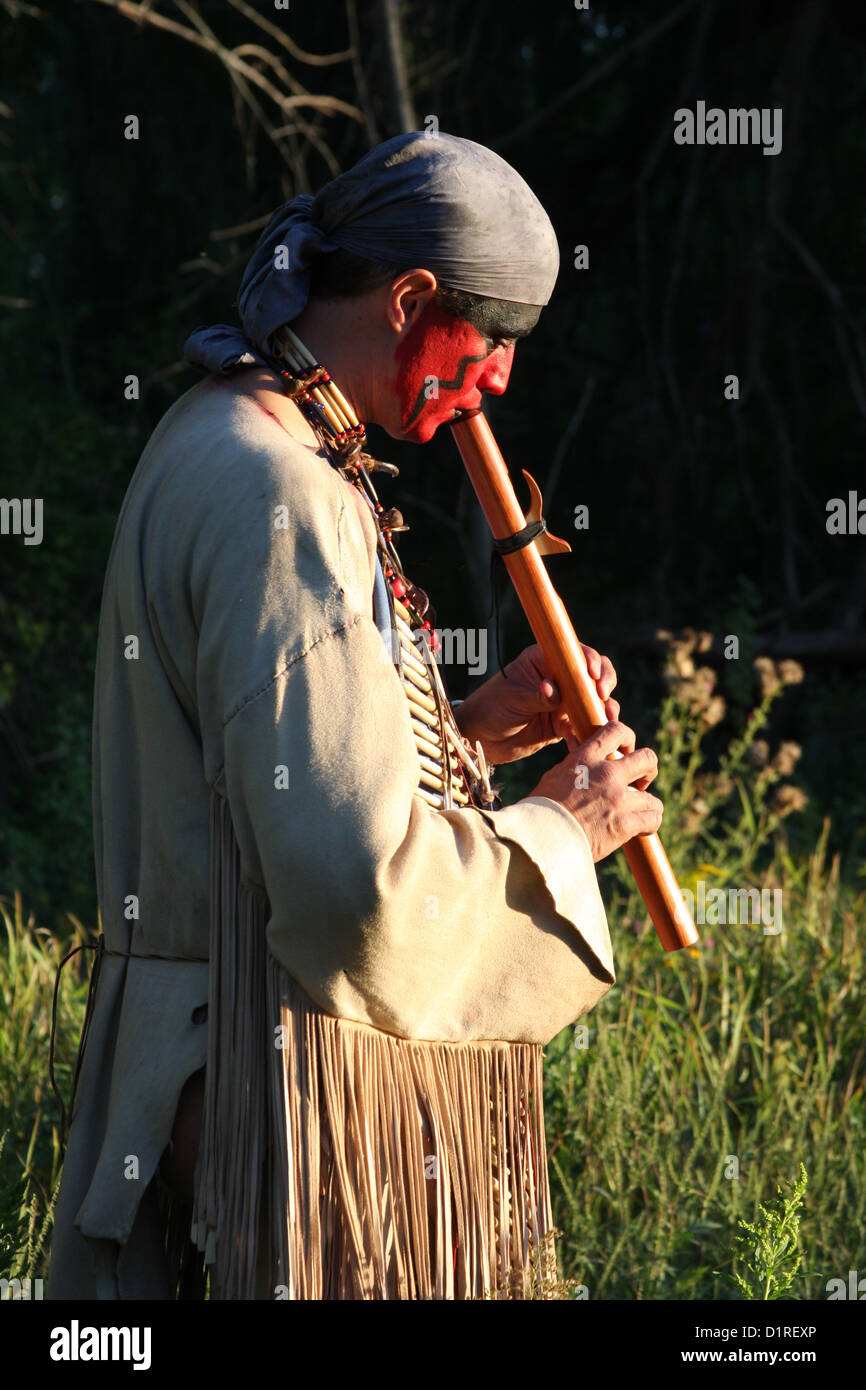 Un Native American Indian uomo giocando un flauto di legno al di fuori nella natura Foto Stock