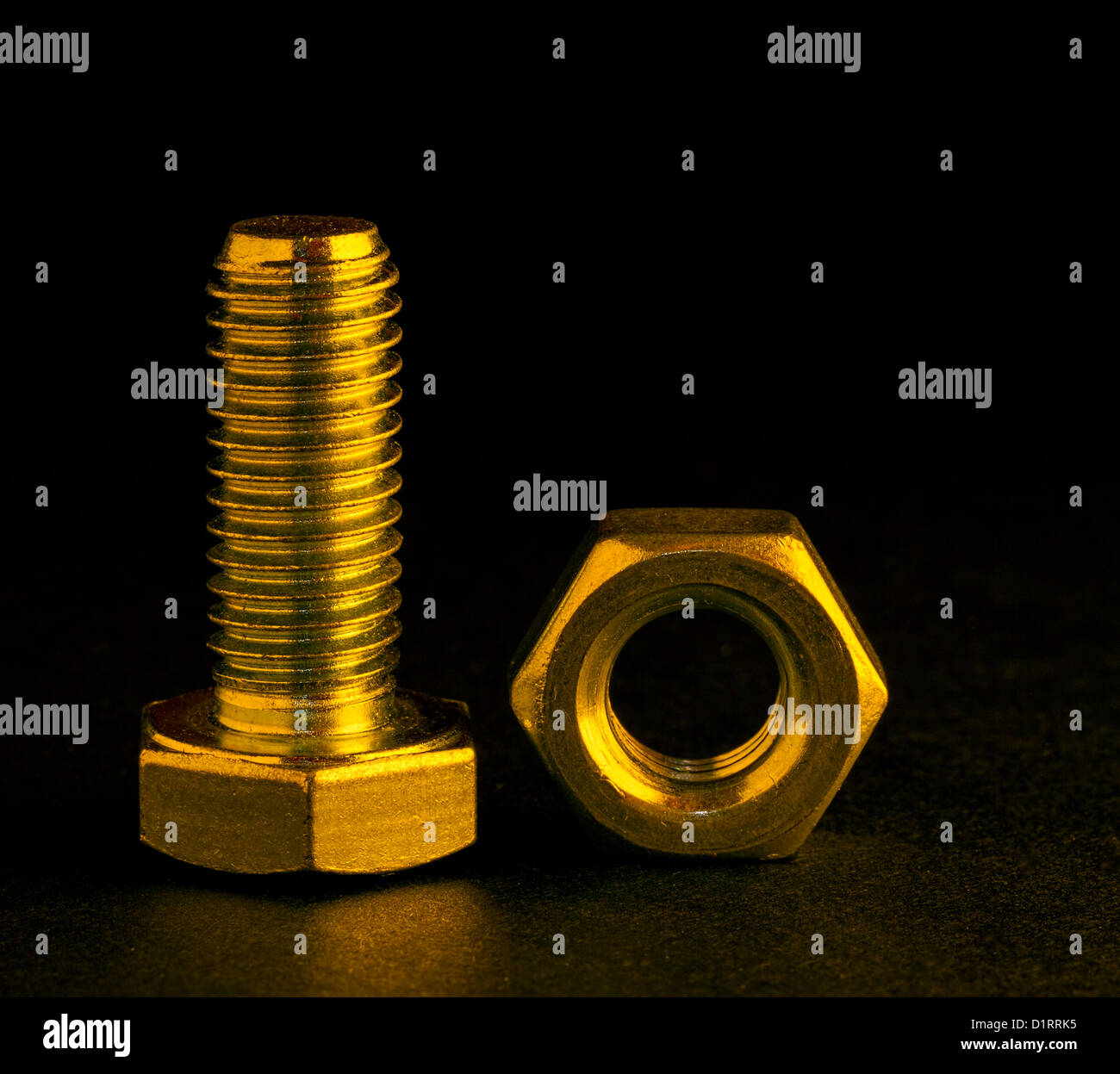 Il dado e il bullone con illuminazione oro su sfondo nero Foto Stock