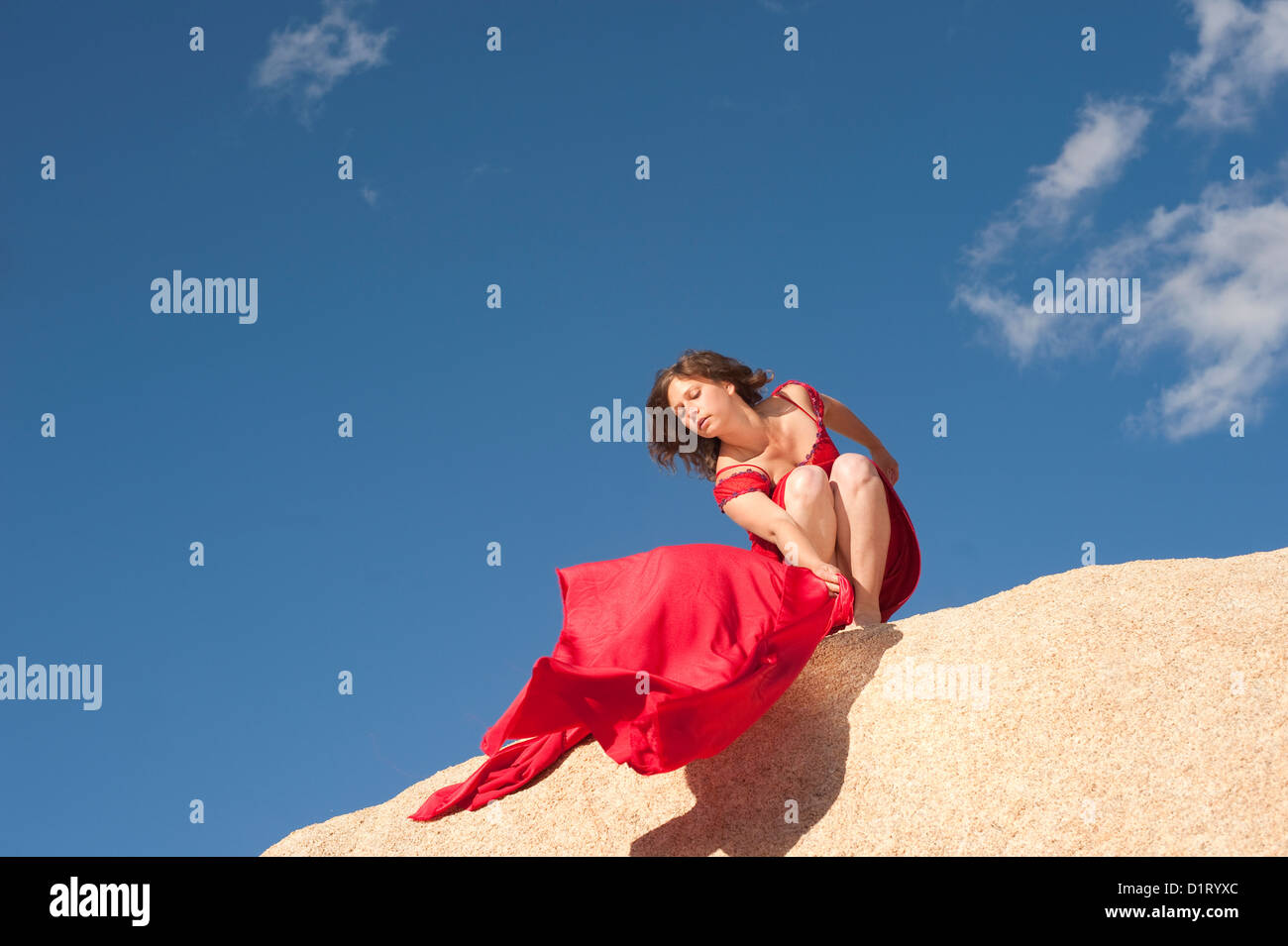 Donna consentendo una sciarpa rossa a soffiare da un bordo di scogliere. Foto Stock