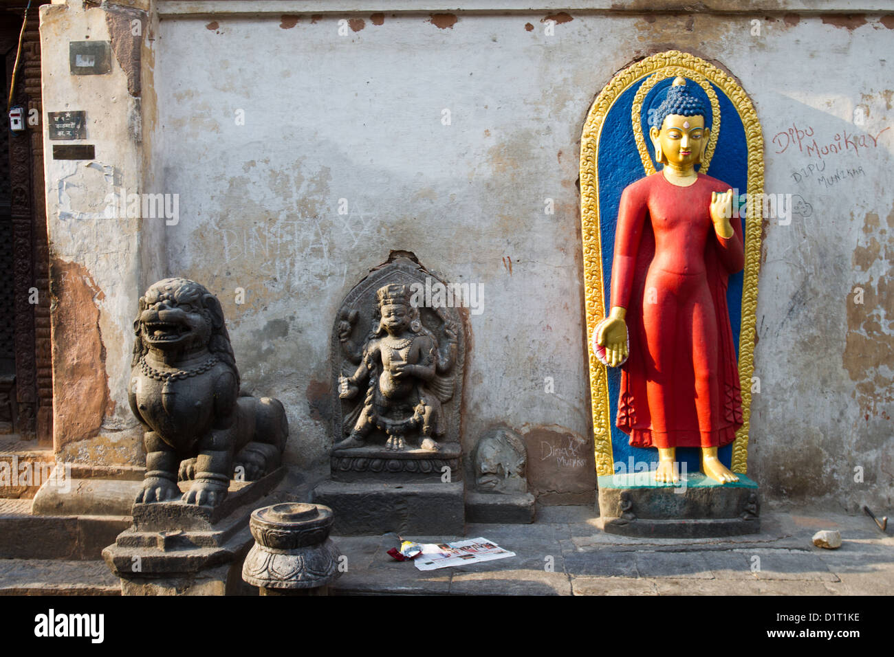 Red statua del Buddha e statue di grigio al tempio Boudhanath Kathmandu Foto Stock