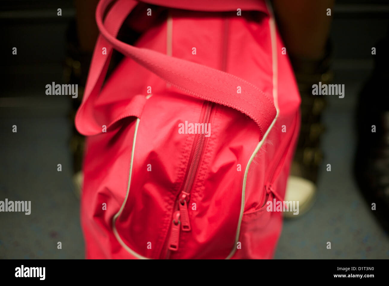 Red borsa sportiva tra le gambe sulla metropolitana di Londra Foto Stock