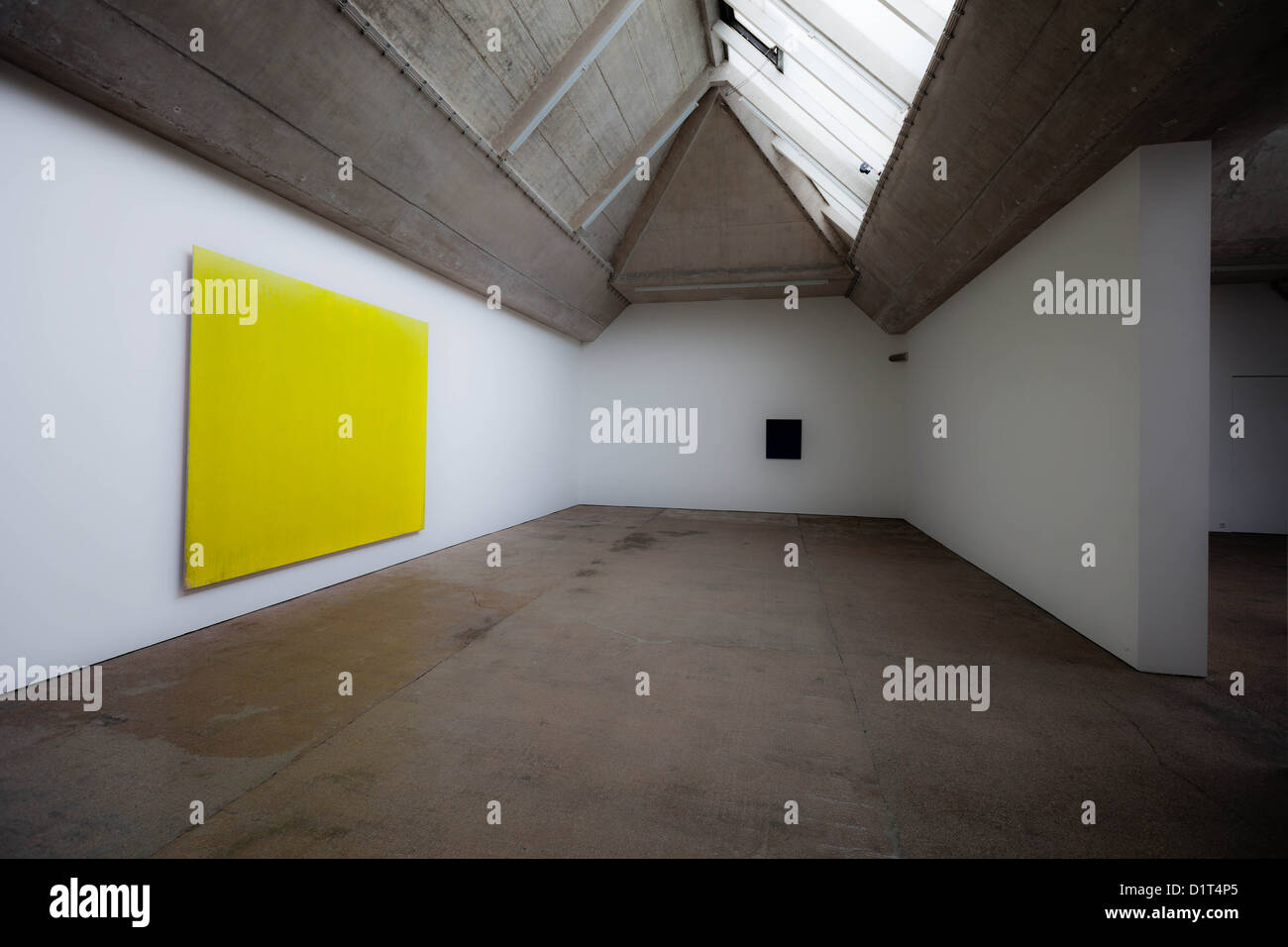Dipinti gialli e neri in una sala espositiva in cemento Foto Stock