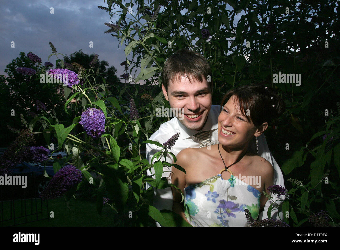 Felice giovane coppia in giardino fioritura arbusto uomo donna dentro amore Foto Stock