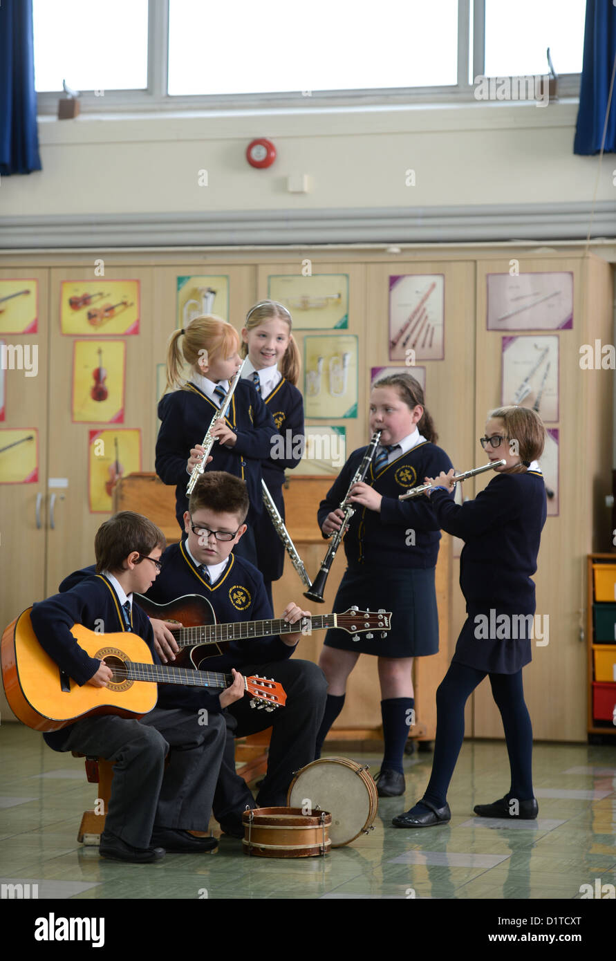 Ragazzi pratica sul loro chitarre durante una lezione di musica la Madonna e San Werburgh Cattolico della scuola primaria a Newcastle-under-Lyme, Foto Stock