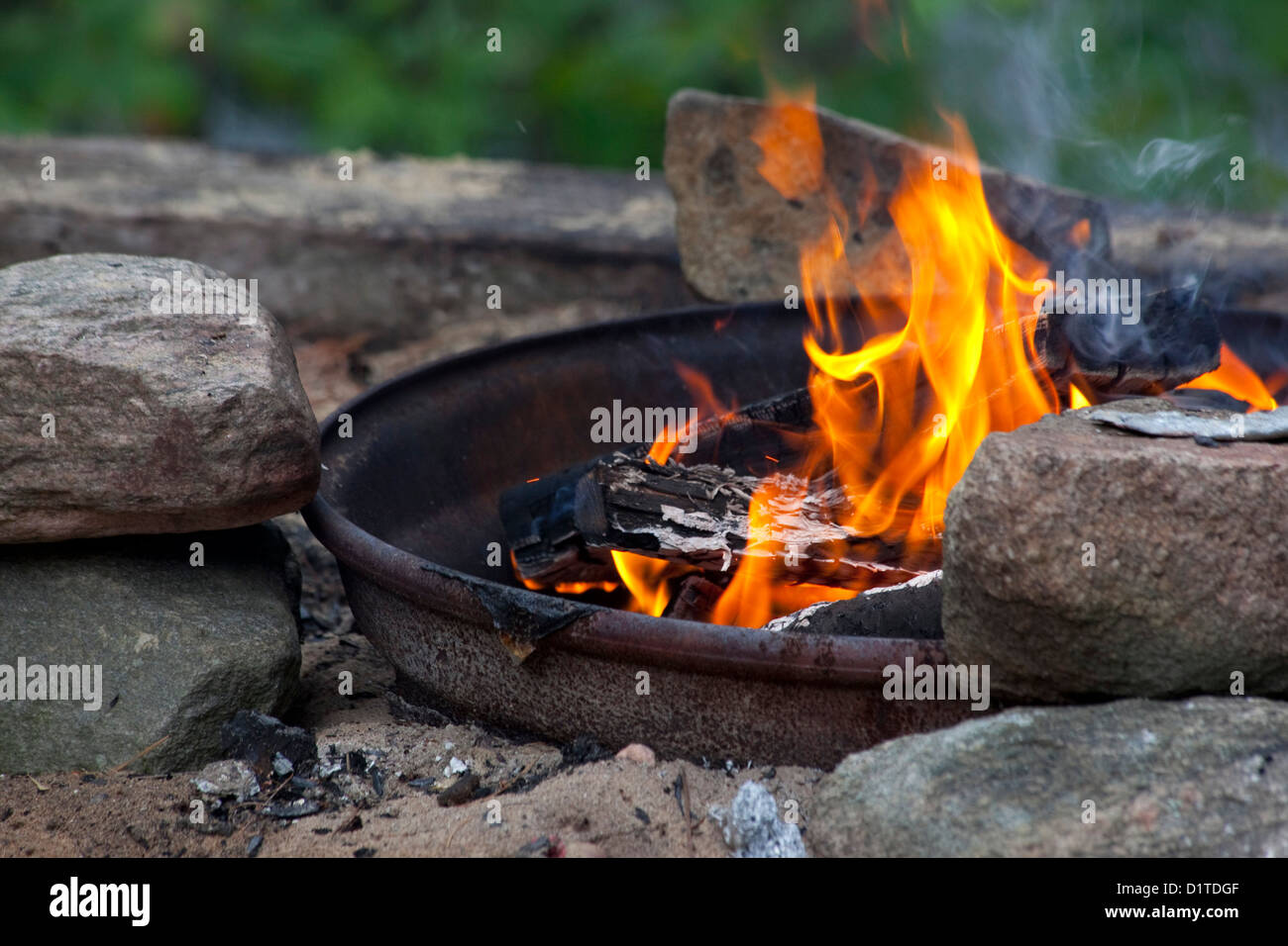 Aprire outdoor una buca per il fuoco brucia il legno accanto a rocce. Foto Stock