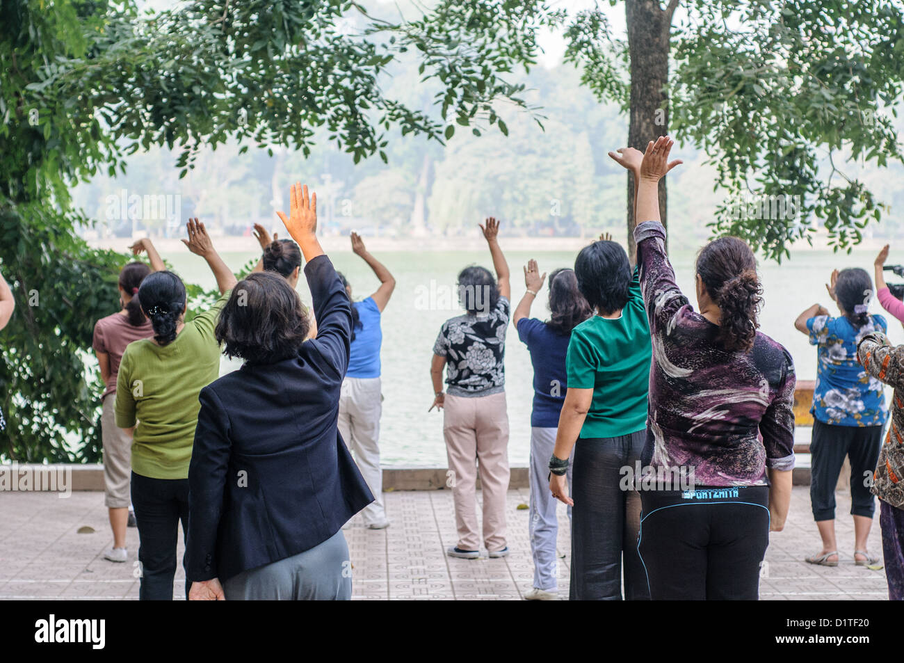 Tai chi Exercise Hoan Kiem Lake Hanoi Vietnam // HANOI, Vietnam — Un gruppo di donne locali fa Tai chi al mattino sulle rive del lago Hoan Kiem nel cuore di Hanoi, Vietnam. Foto Stock