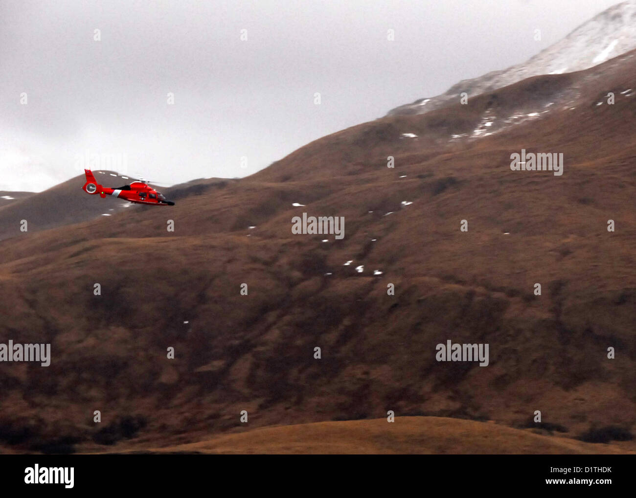 Stati Uniti Costa guardie con il comando unificato ritorno alla guardia costiera Stazione aria Kodiak, Alaska a bordo di un MH-65 Delfino elicottero in seguito un volo su Royal Dutch Shell conica dell'unità di foratura Kulluk gen. 5, 2013. 40 miglia a sud-ovest della città di Kodiak, Alaska, sulla riva di Sitkalidak isola. (U.S. Coast Guard foto di Sottufficiali di prima classe e Travis Marsh/rilasciato) Foto Stock