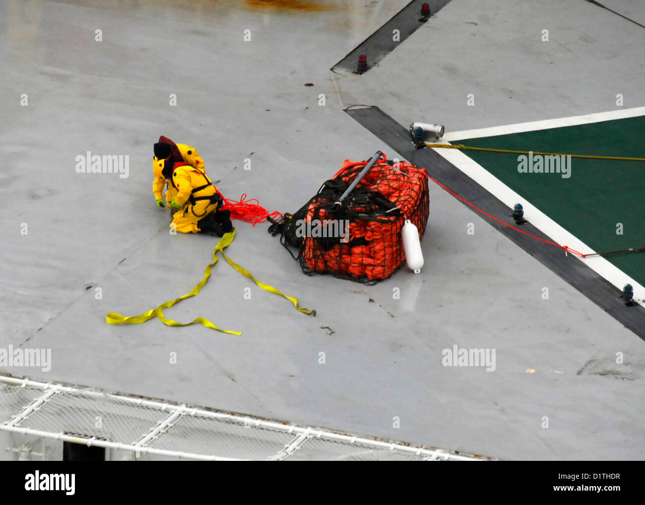 Una squadra di salvataggio a bordo dell'unità di perforazione conica Royal Dutch Shell Kulluk protegge le linee da un sistema di traino di emergenza consegnato da un elicottero MH-60T Jayhawk della Guardia Costiera degli Stati Uniti vicino a Sitkalidak Island, Alaska, il 5 gennaio 2013. L'operazione faceva parte di uno sforzo per aiutare a mettere in sicurezza l'unità di perforazione Kulluk. Foto Stock