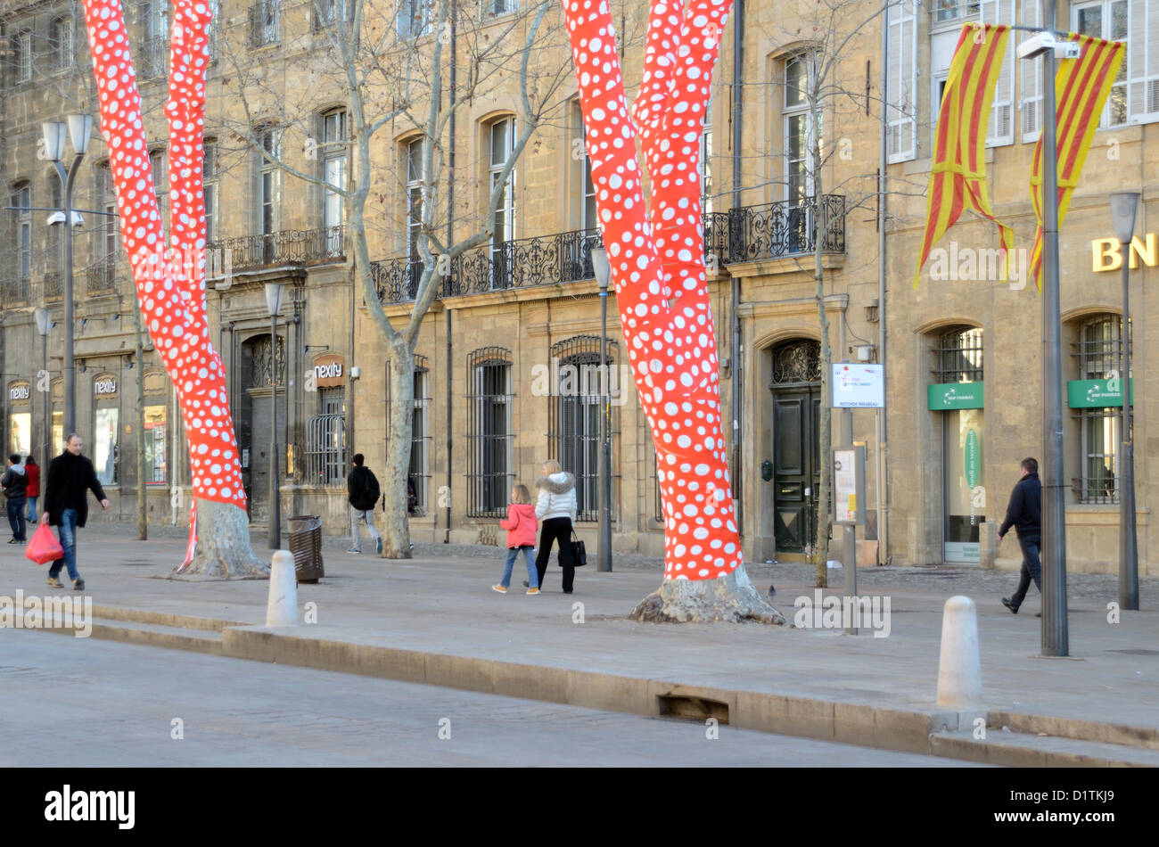 Pedoni passavano oltre gli alberi di platano avvolti di Polka Dot, un'installazione artistica dell'artista giapponese Yayoi Kusama Cours Mirabeau Aix-en-Provence per l'inaugurazione di Marseille-Provence 2013 capitale europea della Cultura. Provenza Francia Foto Stock