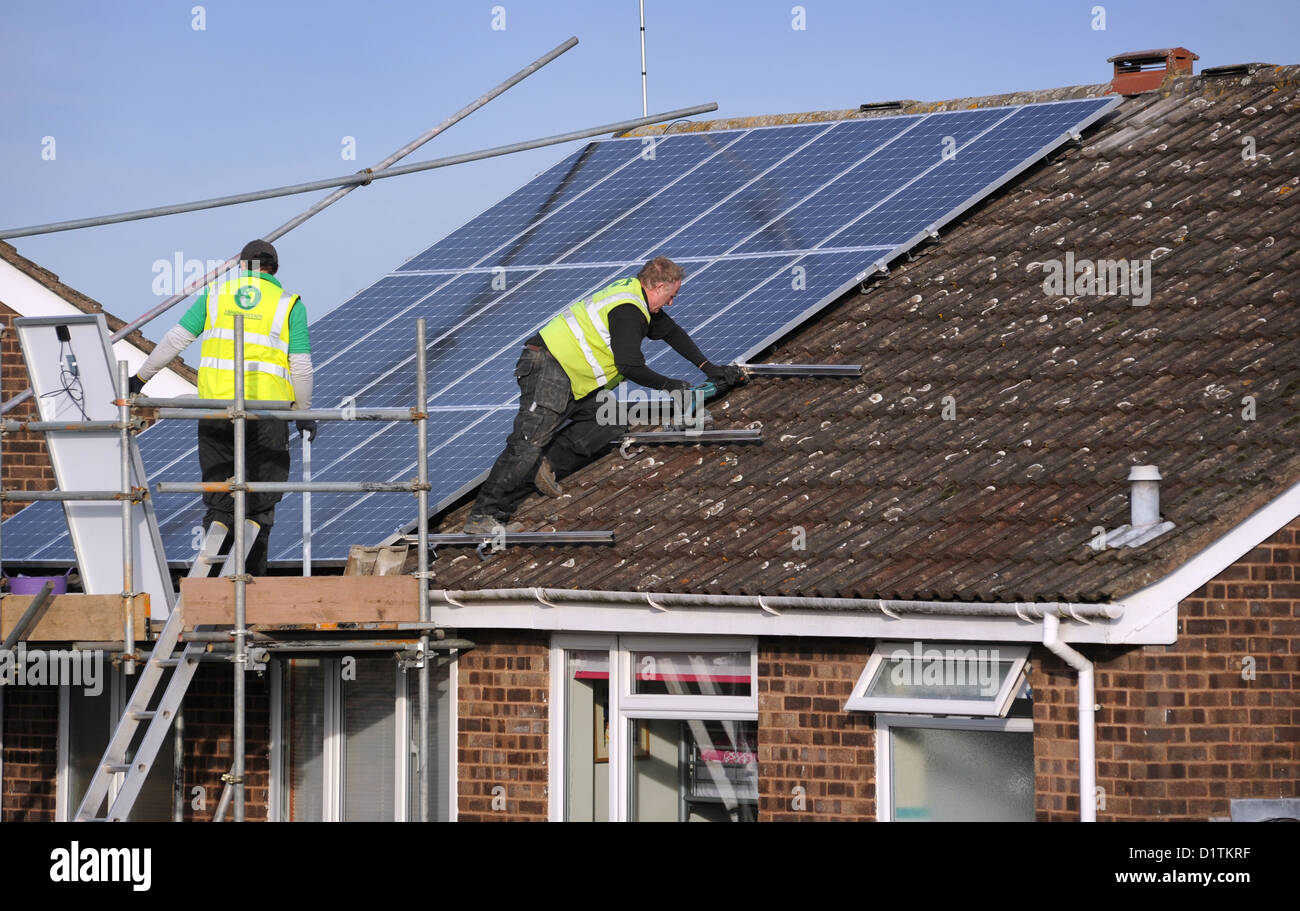 Operai montaggio di pannelli solari per una casa Nazionale Energia del tetto dei costi bollette prezzi SUN POWER elettricità griglia nazionale britannico di riscaldamento Foto Stock