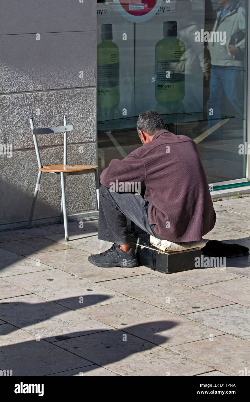 Un lustrascarpe uomo senza i clienti sulle strade di Lisbona, Portogallo. Foto Stock
