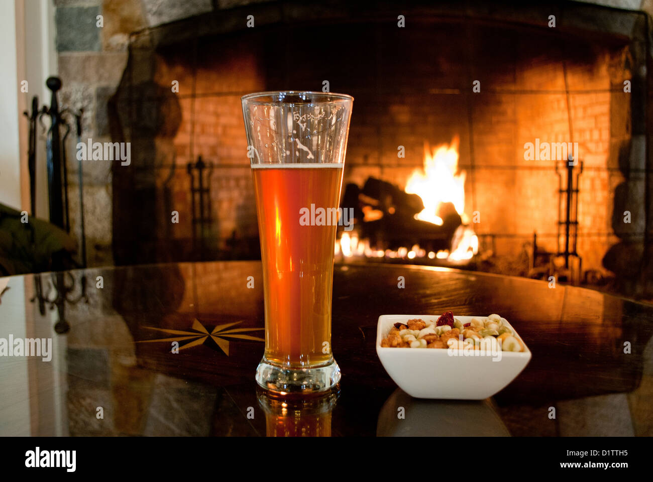 Un bicchiere di birra di fronte al caminetto. Foto Stock