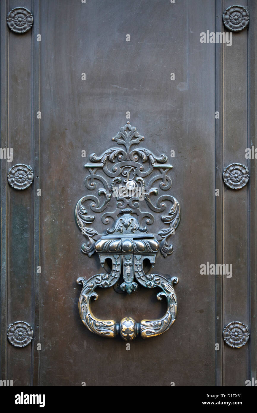 Design elaborato porta in ottone respingente su una porta di legno Foto Stock