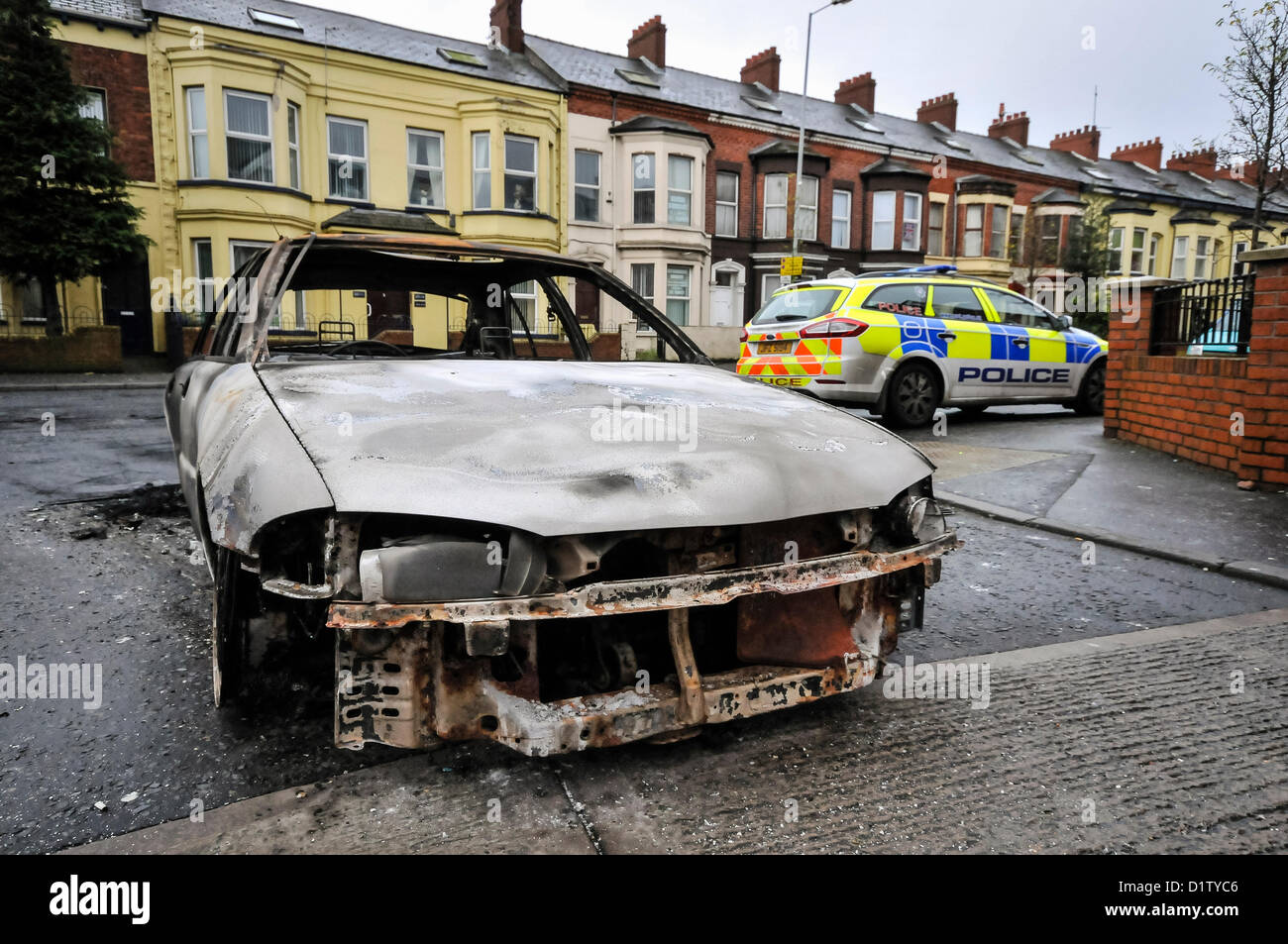 6 gennaio 2013, Belfast, Irlanda del Nord - UNA PSN auto della polizia si siede accanto a un bruciato auto come esso rimane sulla strada Albertbridge in East Belfast dopo una notte di disordini da più di 300 persone. Alamy Live News. Foto Stock