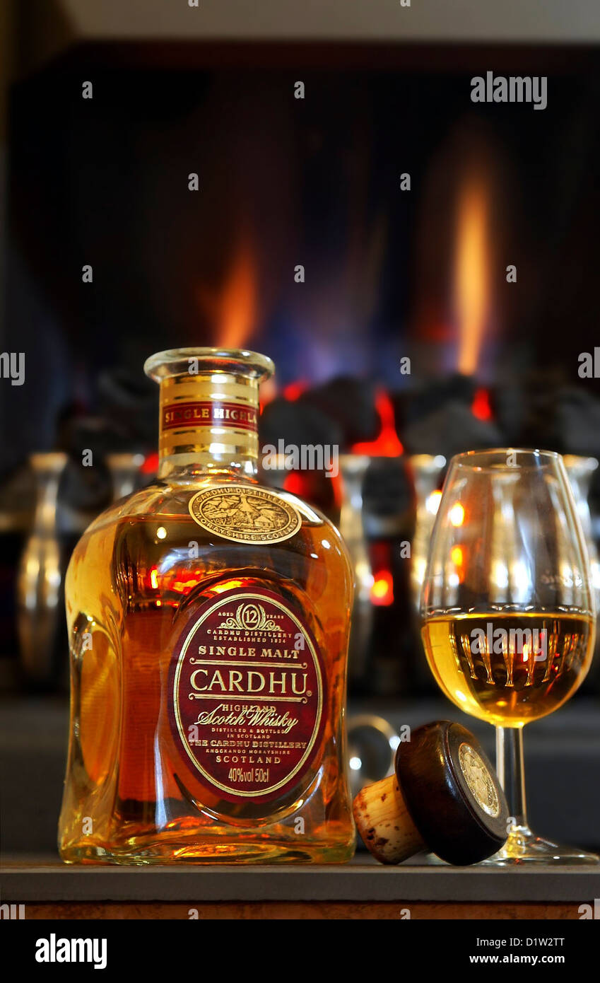 Una bottiglia di vetro e di Cardhu single malt Scotch whisky davanti ad un fuoco aperto Foto Stock